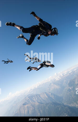 Vier Fallschirmspringer Schlange auf einem Tracking springen oberhalb Locarno, Schweiz mit den Alpen im Hintergrund Stockfoto