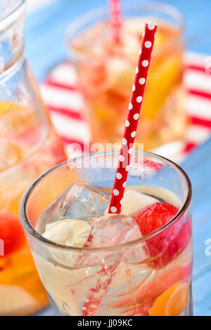 Nahaufnahme von einem Krug und einige Gläser mit erfrischenden spanische Sangria Blanca, weiße Sangria mit frischen Fruchtstücken, auf einem rustikalen Holztisch blau Stockfoto
