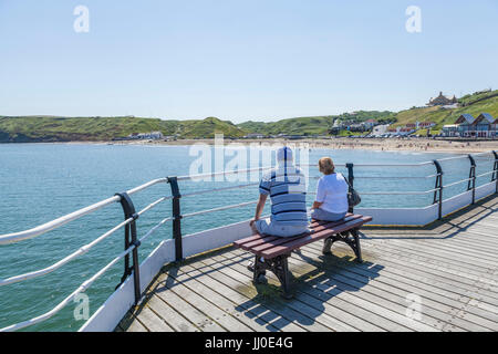 Ein Mann und eine Frau saß auf einer Bank auf dem Pier, Blick auf das Meer bei Saltburn am Meer, England, UK Stockfoto