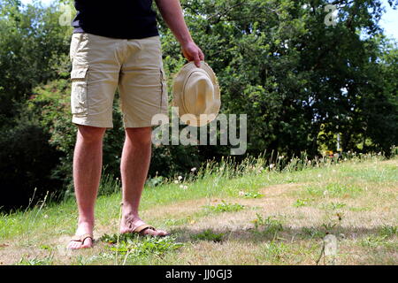 Mann in kurzen Hosen mit einem Hut steht im Hinterhof Stockfoto