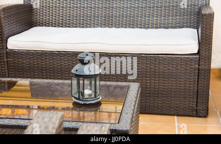 Rattan-Möbel, Sofa Sessel, Couchtisch aus Glas mit Kerze-Halter, Fragment von Terrasse, Veranda, mediterranen Stil, Terrakotta Bodenfliesen, Spanien Stockfoto