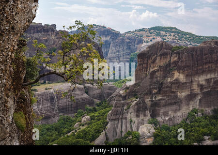 Malerische Aussicht auf die Berge, Klöster und großer Baum auf einem Felsen von Meteora im Sommer, UNESCO-Weltkulturerbe, Trikala, Griechenland Stockfoto