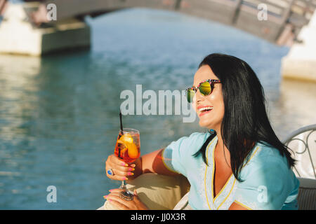 Glücklich schöne Bräunung Frau sitzen und trinken cocktail im Seaside Café, selektiven Fokus Stockfoto