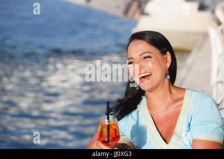 Glücklich schöne Bräunung Frau sitzen und trinken cocktail im Seaside Café, selektiven Fokus Stockfoto