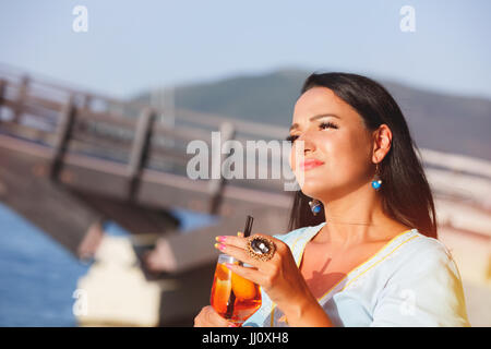 Glücklich schöne Bräunung Frau sitzen und trinken cocktail im Seaside Café, selektiven Fokus Stockfoto