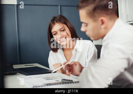 Paar junge Designer arbeiten in modernen Büros, zwei Kollegen diskutieren Spaß-Projekt über einen Laptop, kleines Team Geschäftsleute lächelnd und Blick Stockfoto