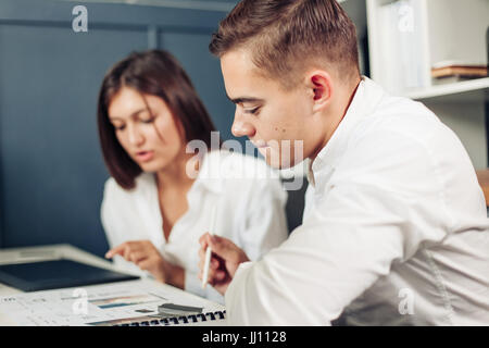 Paar junge Designer arbeiten in modernen Büros, zwei Kollegen diskutieren Spaß-Projekt über einen Laptop, kleines Team Geschäftsleute lächelnd und Blick Stockfoto