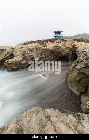 Felsenbucht mit Motion blur Wasser unter Rettungsschwimmer-Turm Leo Carrillo State Beach in Malibu, Kalifornien.