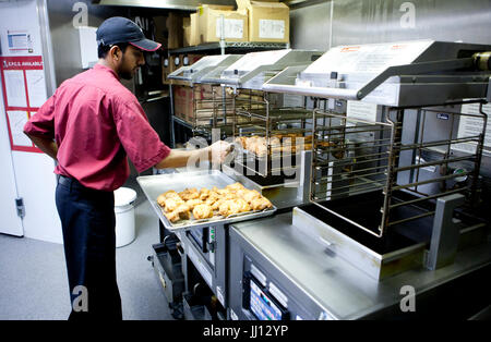 Ein Mitglied des Personals bereitet Brathähnchen bei KFC im England, UK. Stockfoto