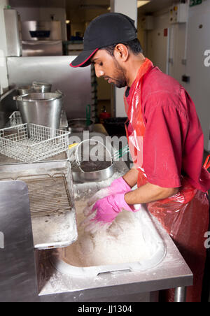 Ein Mitglied des Personals bereitet Brathähnchen bei KFC im England, UK. Stockfoto