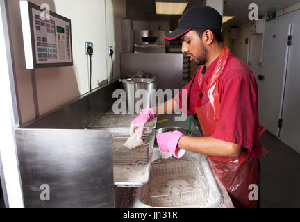 Ein Mitglied des Personals bereitet Brathähnchen bei KFC im England, UK. Stockfoto