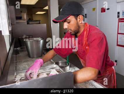 Ein Mitglied des Personals bereitet Brathähnchen bei KFC im England, UK. Stockfoto