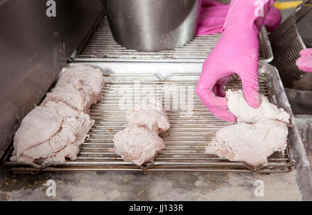 Ein Mitglied des Personals bereitet Brathähnchen bei KFC im England, UK. Stockfoto