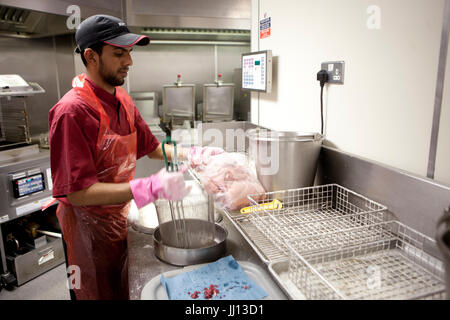 Ein Mitglied des Personals bereitet Brathähnchen bei KFC im England, UK. Stockfoto