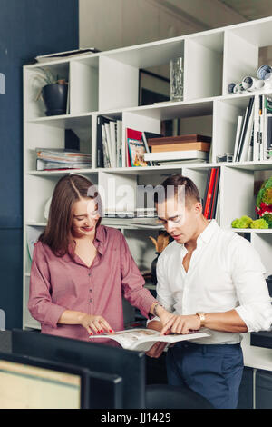 Zwei männliche Studierende Buch über marketing gemeinsam vorbereiten testen in Bibliothek sitzend und Scherz und Spaß. Kreativ blog Stockfoto