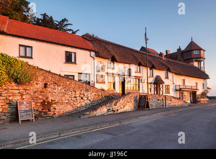 19. Juni 2017: Lynmouth Devon, England, UK - die alten Hütten der Mars Hill mit der aufgehenden Sonne an den Fenstern der Rising Sun Hotel widerspiegelt. Stockfoto