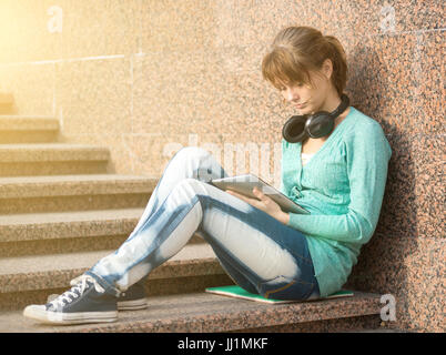 Schöne junge Frau Student mit Notizblock und Kopfhörer. Outdoor-Student. Stockfoto
