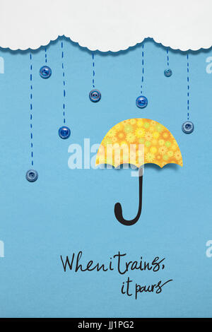 Kreativkonzept Foto eines Regenschirms mit Knöpfe aus Papier auf blauem Hintergrund. Stockfoto