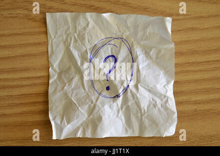 Fragezeichen in ein zerknittertes Papier auf einem Holztisch geschrieben Stockfoto