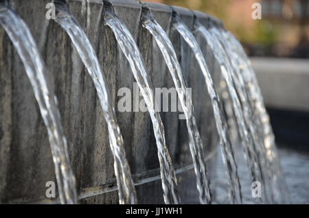 Wasser fließt durch separate Risse aus einem großen Pool, in einem größeren Pool unten. Stockfoto