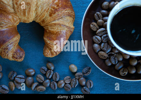 frisch gebackene Croissants und frischem Kaffee Espresso mit Kaffeebohnen ist ein guter Anfang-Arbeitstag. Closeup erschossen Draufsicht von oben Stockfoto