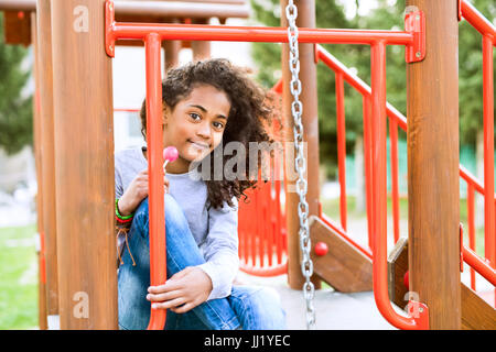 Afroamerikanische Mädchen auf Spielplatz Essen Lutscher. Stockfoto