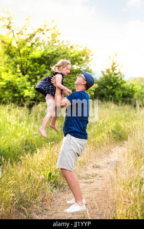 Junger Vater in der Natur, die kleine Tochter in den Armen hielt. Stockfoto