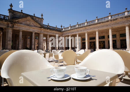 Zwei Tassen auf dem Tisch mit zwei Stühlen gegen eine reine römischen Hintergrund der Kolonnaden. Stockfoto