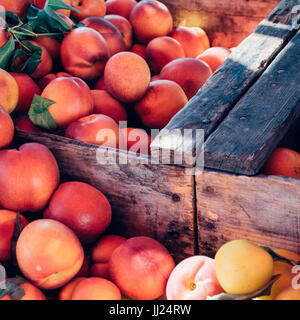 Pfirsiche und Nektarinen in einer Holzkiste in einem Outdoor-Bauernmarkt Stockfoto