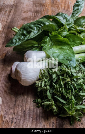 Italienischen Zutaten auf einem Holztisch mit Basilikum, Oregano und grünen Knoblauch. lokal angebauten, organisch, aus dem Bauernmarkt Stockfoto