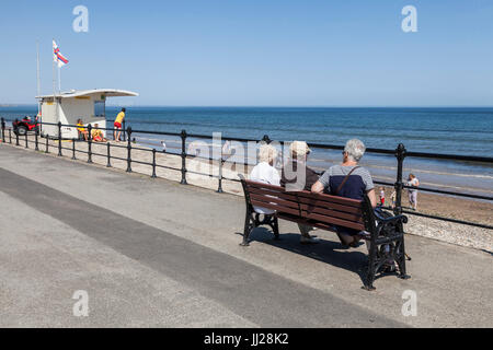 Drei Leute saßen auf einer Bank, Blick auf das Meer bei Saltburn am Meer, England, UK Stockfoto