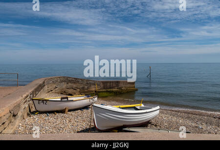 Angelboote/Fischerboote hochgezogen auf dem Schiefer Pebble Beach in Sidmouth, Devon, im Port Royal-Bereich der Strandpromenade. Stockfoto