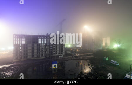 Starker Nebel in der Nacht auf einer Baustelle mit einem Skelett von einem Hochhaus im Bau Stockfoto