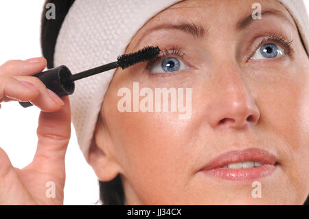Closeup Portrait Reife Frau Mascara auf die Wimpern auftragen. 50-Jahr-alte Frau setzen Mascara vor Spiegel Stockfoto