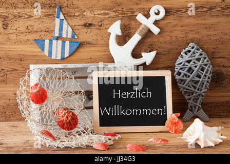 Tafel mit nautischen Sommer Dekoration und hölzernen Hintergrund. Deutsche Text Herzlich Willkommen heißt willkommen. Fische, Anker, Muscheln und Netzstrümpfe für Stockfoto