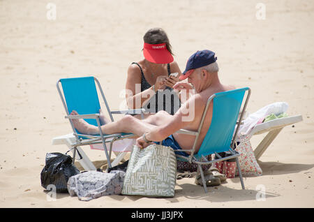 Boscombe, Bournemouth, Dorset, Großbritannien, 18.. Juli 2017. Seior Pärchen sitzt bei heißem Wetter auf Strandstühlen. Stockfoto