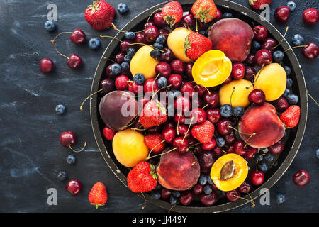 Frische reife Sommerbeeren und Früchte (Pfirsiche, Aprikosen, Kirschen und Erdbeeren) auf Tablett Stockfoto