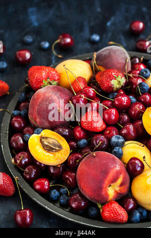 Frische reife Sommerbeeren und Früchte (Pfirsiche, Aprikosen, Kirschen und Erdbeeren) auf Tablett Stockfoto