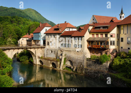 Älteste Steinbrücke in Slowenien Kapuziner Brücke und Kirche Glockenturm am Fluss Selca Sora mit steinernen Mauern umgebene Flussufern in Skofja Loka Dorf Stockfoto