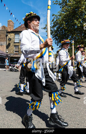 Traditionelle englische Volkstänzer, Yateley Morris Seite tanzen auf der Straße in der mittelalterlichen Stadt Sandwich während des Folk und Ale-Festival. Holding Polen. Stockfoto