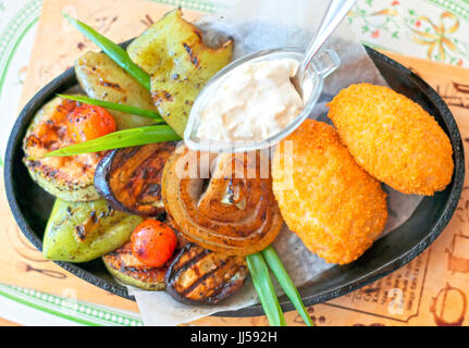 Zwei Chicken Kiev mit gebratenem Gemüse. Stockfoto