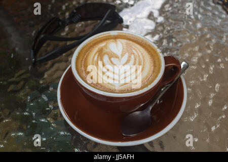 Heißen Kaffee Latte mit schönen Latte Art on Glaskeramik in lokalen Indy Kaffee Café in Thailand. Stockfoto
