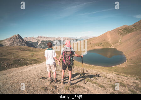 Paar der Wanderer auf den Berg Top Blick auf blaue See und die Berge Gipfel. Sommer Abenteuer in den Alpen. Weitwinkel-Ansicht von oben, getönten Bild V Stockfoto