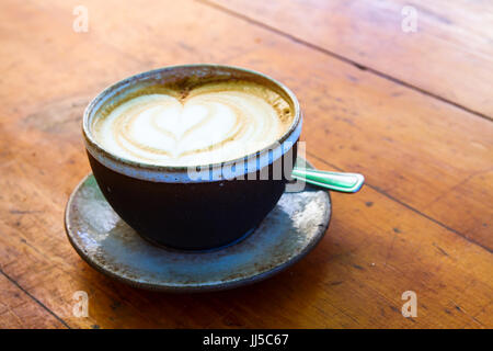 Schöne Tasse Kaffee Cappuccino auf hölzernen Tisch im Cafe Stockfoto
