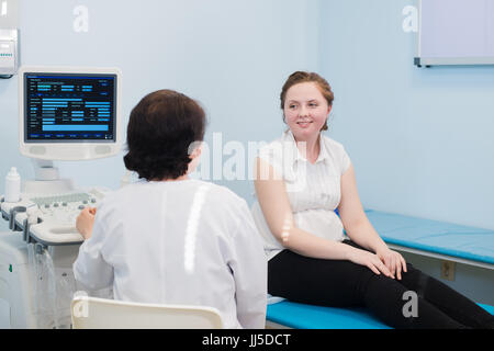 Zufrieden schwangere Frau, die ärztliche Visite mit Ultraschalldiagnostik. Stockfoto