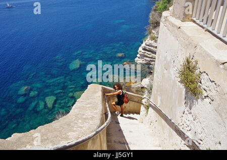 Junge weibliche Touristen absteigend die Treppe geschnitzt in den Klippen von Bonifacio, unterhalb der mittelalterlichen Burg. Stockfoto