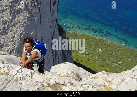 Weibliche Wanderer (junge Erwachsene) auf dem Weg zum Gipfel des Tavolara, Lookng hinunter in Richtung Meer. Stockfoto