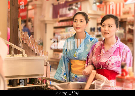 Japanerinnen Wahl casual street Food snack vor Garküche im Lebensmittel-Straße in Japan. Schönheit asiatischen Freundinnen tragen traditionelle Kimono d Stockfoto