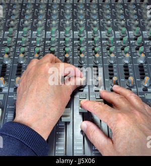 Erfahrene Hände Betrieb Fader, Knöpfe und Regler auf eine analoge Musik mischen und Schreibtisch in einem Studio aufzunehmen Stockfoto