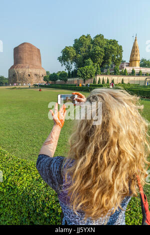 Eine Frau, die ein Bild der Dhamekh Stupa in Sarnath, Indien mit ihrem iPhone. Stockfoto